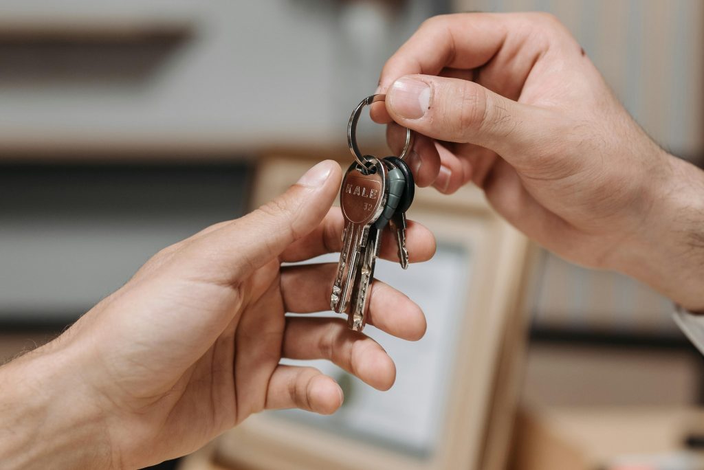 A close-up image of two hands exchanging a set of keys indoors.
